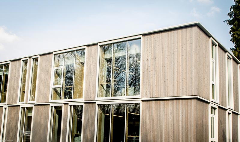 Vue de la façade en bois avec de nombreuses fenêtres du nouveau laboratoire.