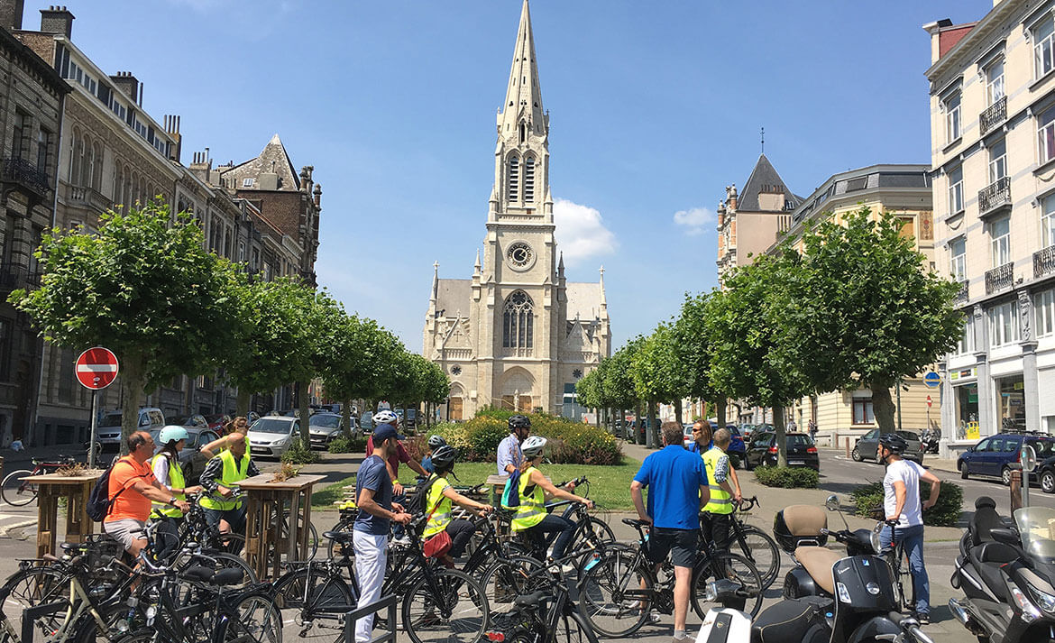 Un groupe de cycliste à l'arrêt sur une place, une église en arrière plan