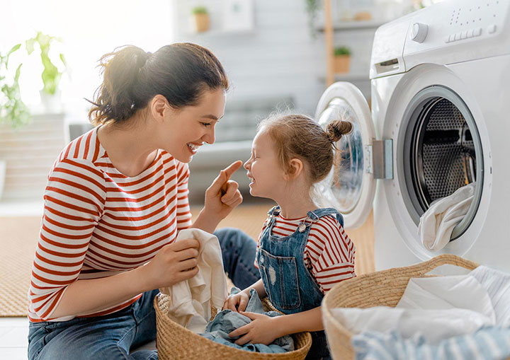 Une femme et une petite fille devant une machine à laver.