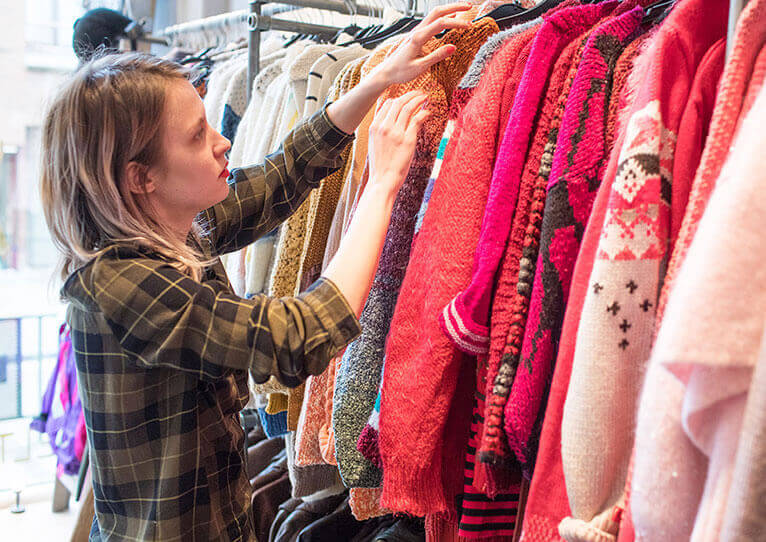 Une femme cherche un vêtement dans un magasin de seconde main