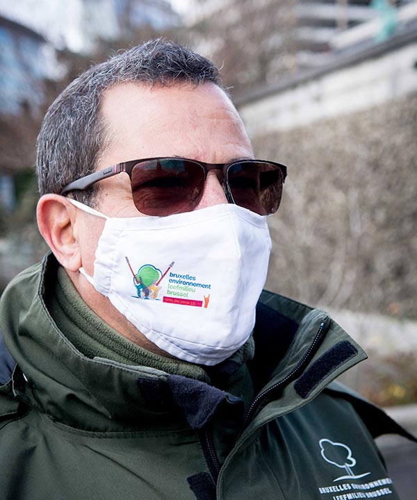 Un gardien de parc porte un masque avec le logo de Bruxelles Environnement.