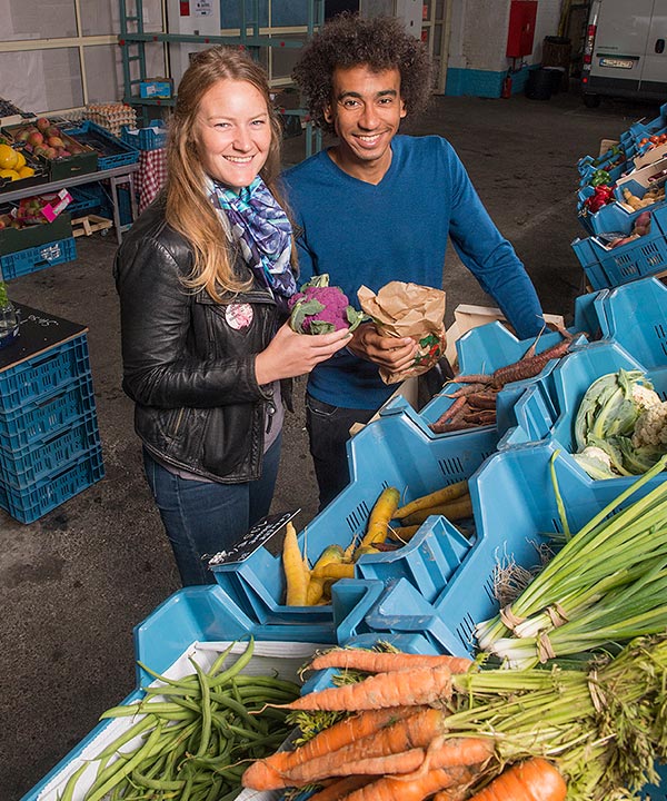 Une femme et un homme achètent des légumes locaux.